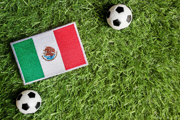 Flat lay of Mexico national flag patch and classic soccer ball on green grass. Symbolic of Mexican sports pride and international football tournament. Top view with copy space. © The Dell Shot by SJ
