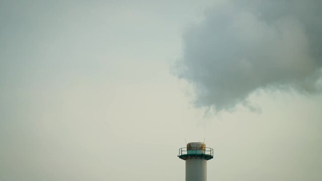 Power plant stack with dense smoke billowing aggressively upward. Industrial emissions, hazardous air pollutants and global warming concept. Environmental degradation and industry impact