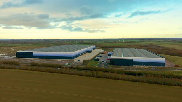 Extensive logistics warehouses operating distribution infrastructure across industrial farmland. Powerful fulfillment centers coordinating cargo flow warehousing and transport operations. Advanced