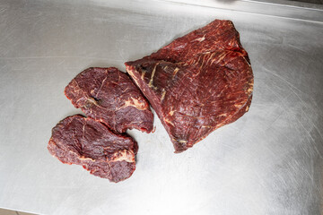 Fototapeta premium Top view of raw beef primal cut and steaks on stainless steel