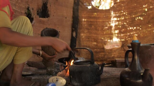 Une femme met de la poudre de caf&eacute; dans une cafeti&egrave;re typique pour la cuisiner, en Ethiopie