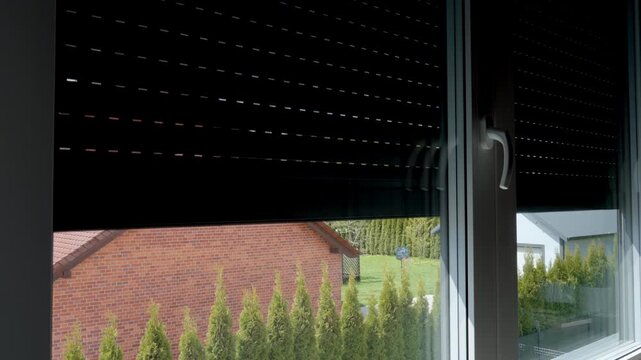 Automatic blackout blinds covering window in room. Electric roller shutter closing on window in apartment. Concept of home privacy sunlight control security and exterior shading