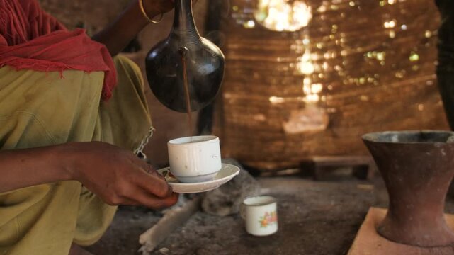 Une femme sert du caf&eacute; fait maison dans une tasse dans une cabane dans la for&ecirc;t, en Ethiopie