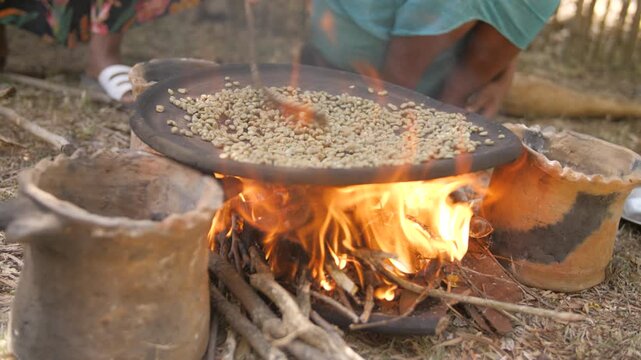 Une femme fait cuire des grains de caf&eacute; dans une casserole au-dessus d&rsquo;un feu ext&eacute;rieur, en &Eacute;thiopie 