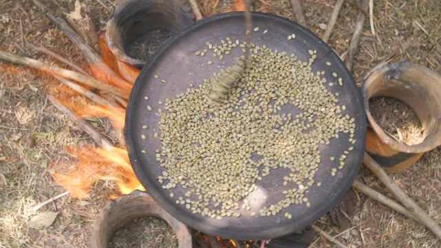 Une femme fait cuire des grains de caf&eacute; dans une casserole au-dessus d&rsquo;un feu ext&eacute;rieur, en &Eacute;thiopie 