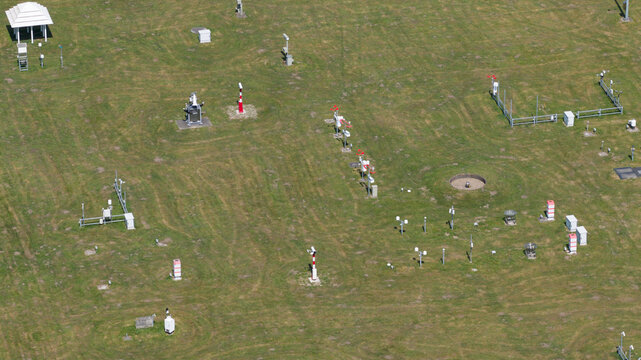 Aerial view of the KNMI meteorological measurement field with various weather sensors and instruments on a green lawn in De Bilt, Utrecht, Netherlands.