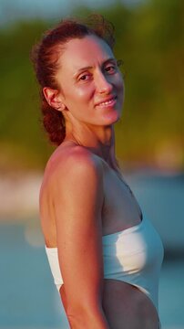 Portrait of beautiful happy woman in white bicini at beach at sunset, outdoor on holiday in summer. Woman with smile at vacation in paradise island Mauritius