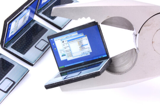 Computer repair concept with miniature laptops in the jaws of a pair of pliers tool. Technology servicing and the right to repair equipment concepts on a white background