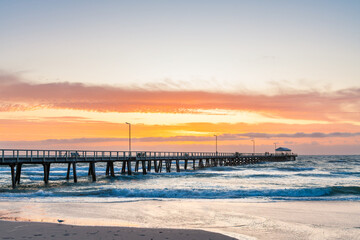 People walking along Henley Beach Jetty during a stormy dramatic sunset viewed from the shoreline in Adelaide, South Australia. © myphotobank.com.au