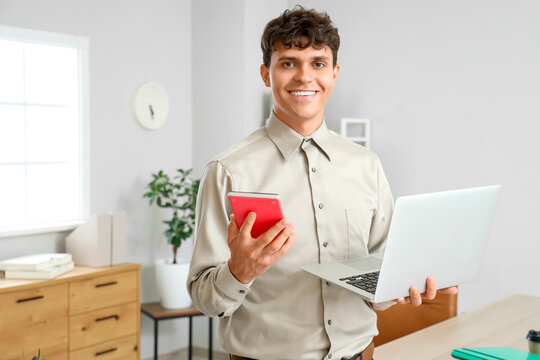 Male accountant with calculator and laptop in office