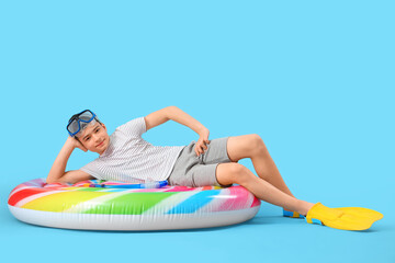 Cute little happy boy with inflatable mattress, snorkeling mask and flippers on blue background © Pixel-Shot