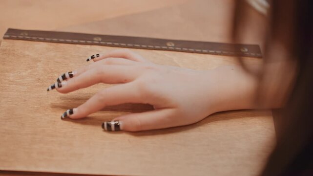 Hand with striped nails on folder, student hesitates before opening journal, barista glances from background, editor studies layout, soft amber light and blurred hair silhouette create cinematic mood