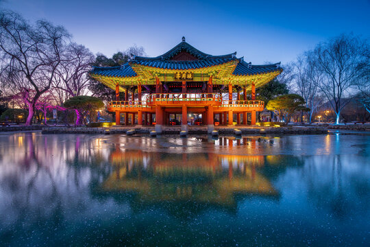 Serene twilight view of the illuminated Gwanghallu Pavilion overlooking a calm pond surrounded by bare winter trees and glowing ground lanterns in Namwon.