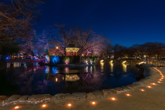 Serene twilight view of the illuminated Gwanghallu Pavilion overlooking a calm pond surrounded by bare winter trees and glowing ground lanterns in Namwon.
