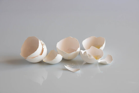 A white eggshell lies on a smooth surface. Easter concept, farming, diet.