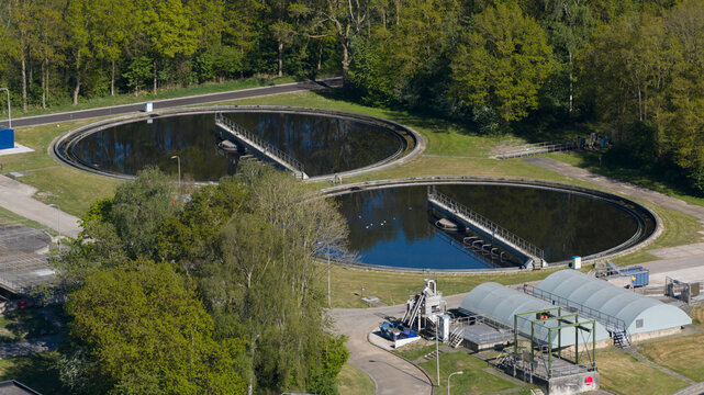 Aerial view of the RWZI Echten wastewater treatment plant with circular clarifier tanks and green trees in Hoogeveen, Drenthe, Netherlands.