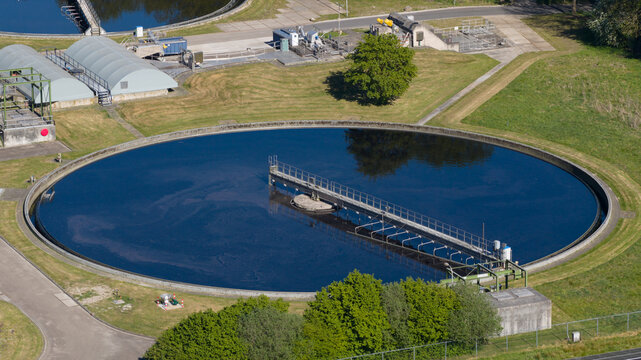 Aerial view of the RWZI Echten wastewater treatment plant featuring a large circular sedimentation tank and industrial facilities in Hoogeveen, Drenthe, Netherlands.