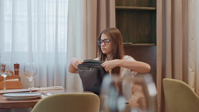 Caucasian writer opening laptop at bistro table, adjusting backpack and case, poised with glasses and steady focus, soft curtain backdrop and blurred foreground, editorial mood and creative