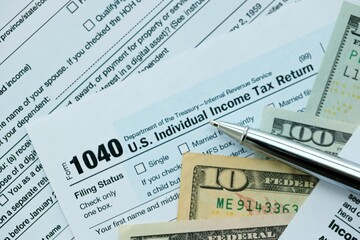 Obraz premium 1040 Individual Income tax return form and pen with dollars money bills on accountants table