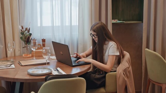 Caucasian freelancer working at bistro table, laptop active, drafting content, coding layout, sipping coffee, ambient evening light, organized notebook, headphones nearby, focused startup hustle