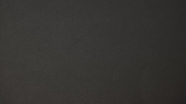 Looping retro-style black paper texture animation with subtle flicker and film grain. Vintage cinematic background for overlays, titles, and motion graphics.