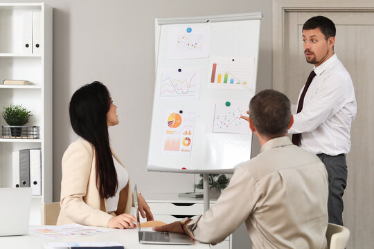 Male business consultant giving presentation to his colleagues in office