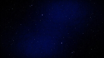 An abstract blue night sky background featuring a starry galaxy and glowing nebula dust scattered across a dark cosmic universe © Hameed-Ahmed