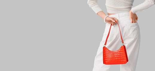 Naklejka premium Beautiful young woman holding red leather bag on light background with space for text, closeup