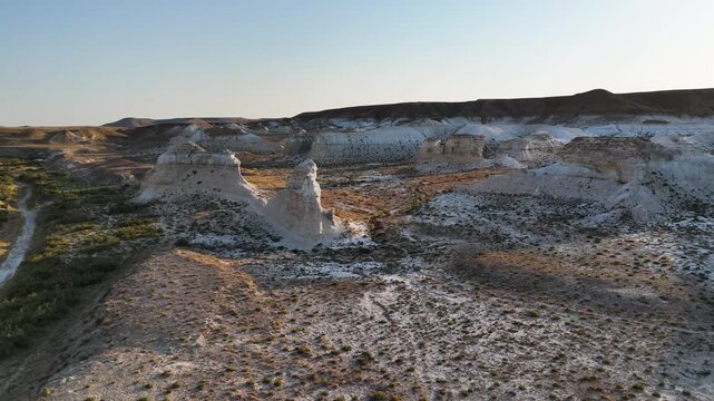 Drone flyover above bizarre chalk outcrops of the ancient Tethys Ocean. Top view of white soil, chalk textures, and steppe grass in the Mangystau desert. A unique Kazakhstan landscape showcasing 