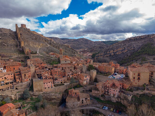 Fototapeta premium Panoramic view of Albarracin, a well-preserved medieval town in Aragon, Spain, featuring red-ochre stone buildings, ancient city walls, and a hilltop castle set among rugged hills
