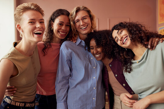 Group of diverse friends smiling and hugging in a cozy cafe, celebrating friendship