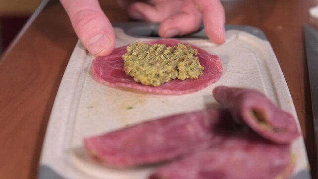 Making a snack with deli meat and spread in a kitchen setting in the afternoon