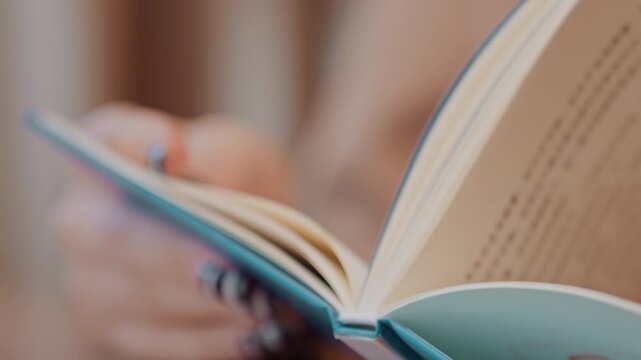 Closeup hands flipping teal book pages, warm soft lighting, shallow depth of field, fingers turning paper and tracing margins, cozy home study vibe, thoughtful reader pausing between lines, focus