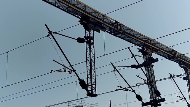 Handheld shot of railway overhead catenary wires and support structures. Ideal for transport infrastructure, electrification systems, engineering, and industrial visuals.