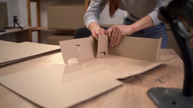 Female Hands assembling a brown cardboard box, top view. process of sustainable business and eco-friendly logistics.