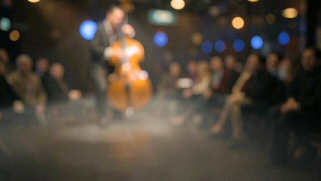 Live music performance with cello player and audience in a dark venue