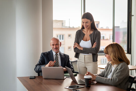 Group of business people with laptops in a modern conference room and having business meeting