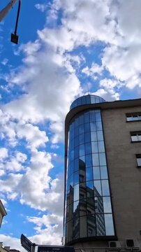 Clouds reflecting in glass office buildings against blue sky, modern urban architecture with mirrored windows and skyscrapers in city center, business district facade with cloud reflection and