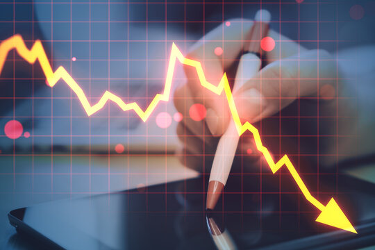Sharp downward stock market graph over digital device with hand holding pen, symbolizing financial decline and global crisis trends.