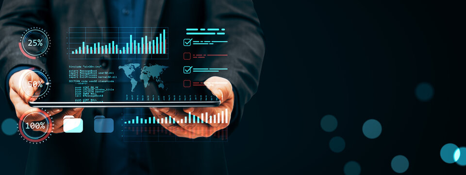 Business professional holding a digital tablet displaying virtual analytics, charts, graphs and data visualization on dark abstract background.