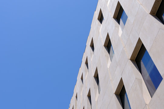 Modern Stone Building Facade with Geometric Diamond Relief Pattern Against Blue Sky Low Angle
