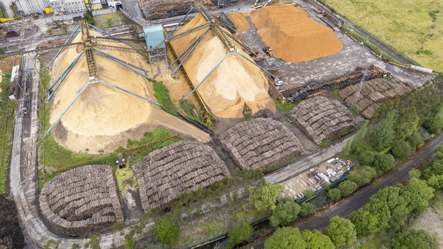 Aerial view of Biofabrica de Ence with large piles of wood chips and stacks of logs processed by industrial machinery in Pontevedra, Pontevedra, Spain.
