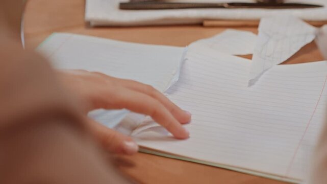 Hands tearing paper over notebook surface, slow measured movements, fingertips folding and peeling sheet, ambient cafe light, tableware blurred in background, roles assistant organizing receipts,