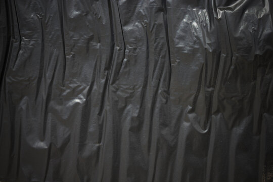 The texture or background of the black crumpled polythene of the package.