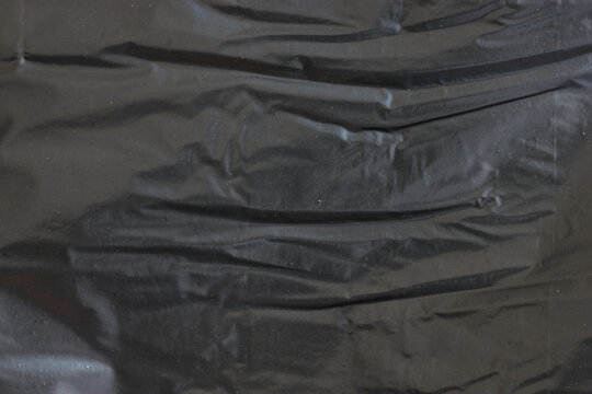 The texture or background of the black crumpled polythene of the package.