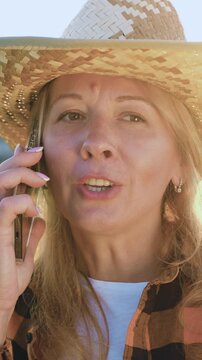 Businesswoman talking on phone near the wheat field. Portrait of modern agronomist woman has conversation with business partners or clients in a field at sunset. Professional female farmer talking