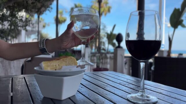 Primer plano de la mano de mujer agarrando su copa en una terraza exterior