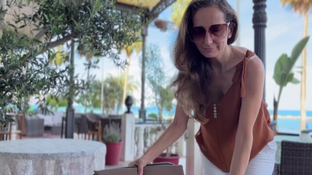 Mujer llegando a la terraza del paseo mar&iacute;timo y sent&aacute;ndose