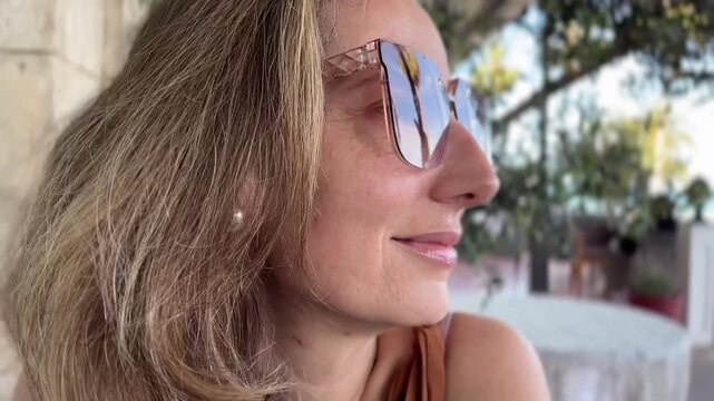 Primer plano de mujer poni&eacute;ndose las gafas de sol en exterior