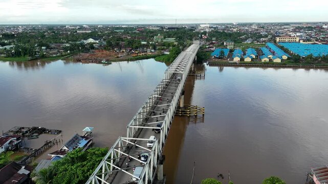 A view from atop the steel truss bridge spanning the Brown River along the urban riverfront with traffic in West Borneo, Indonesia.